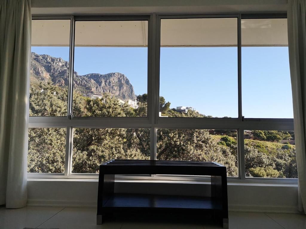 A room with a large window, a bench, and a view of a mountainous landscape.