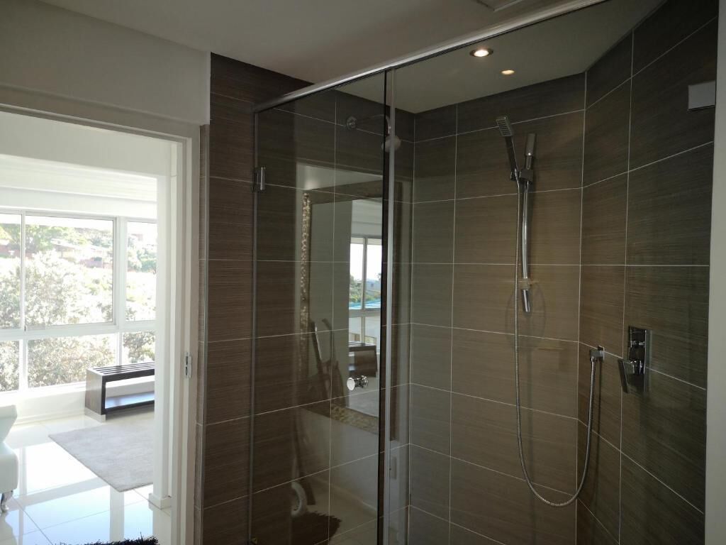 Un baño moderno con cabina de ducha de vidrio, ducha de mano y grifo empotrado.