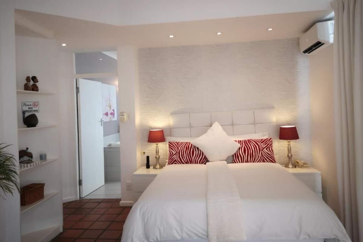Une chambre d’hôtel équipée d’un lit, de deux lampes de chevet, d’une tête de lit et d’un climatiseur fixé au mur.