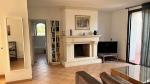 A living room with a fireplace, a television, a sofa, and a bookshelf. - 90m2 apartment (1st floor) in Port d'Alon, 4 persons, dogs welcome. (Saint-Cyr-sur-Mer)