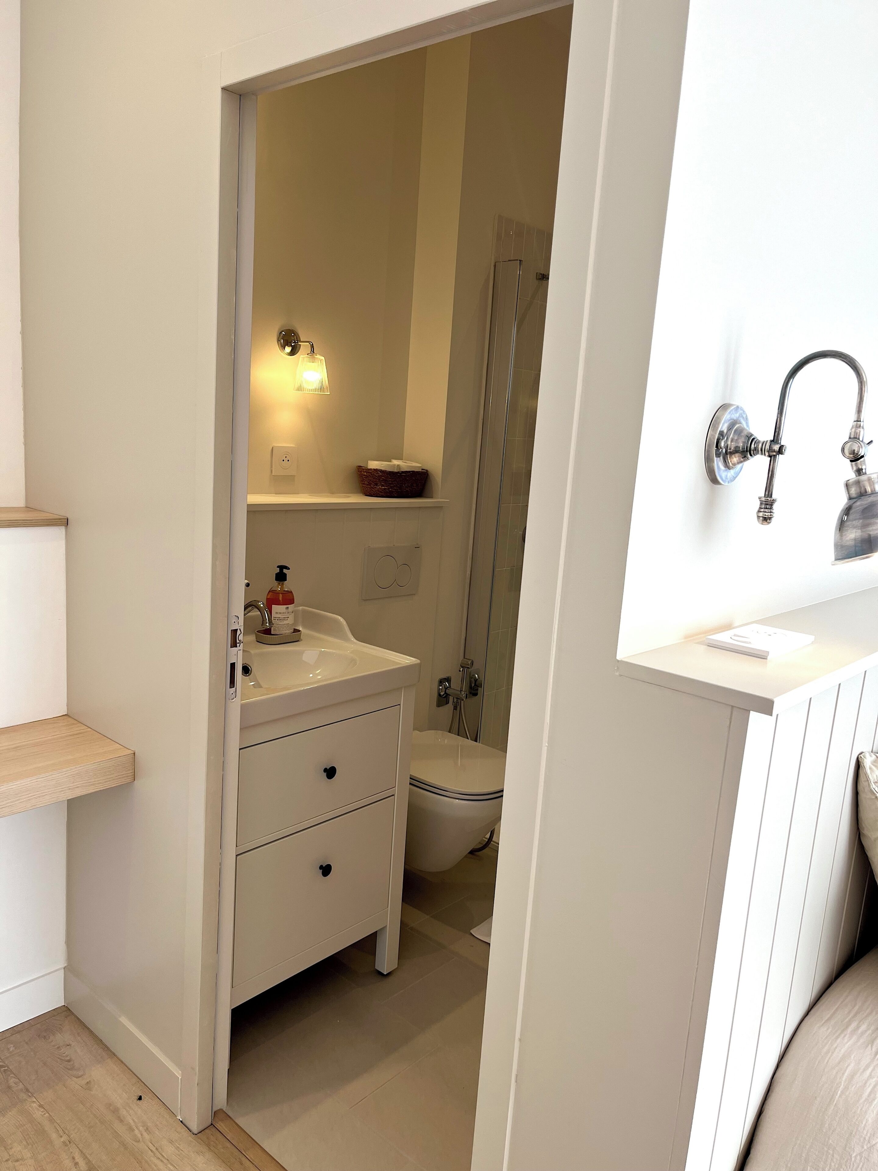 Un bagno con lavandino bianco, uno specchio, una doccia e un WC.