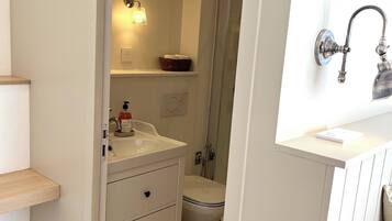 Un bagno con lavandino bianco, uno specchio, una doccia e un WC.