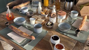 Una mesa de madera con diferentes alimentos para el desayuno, como pan, mantequilla y salsas.