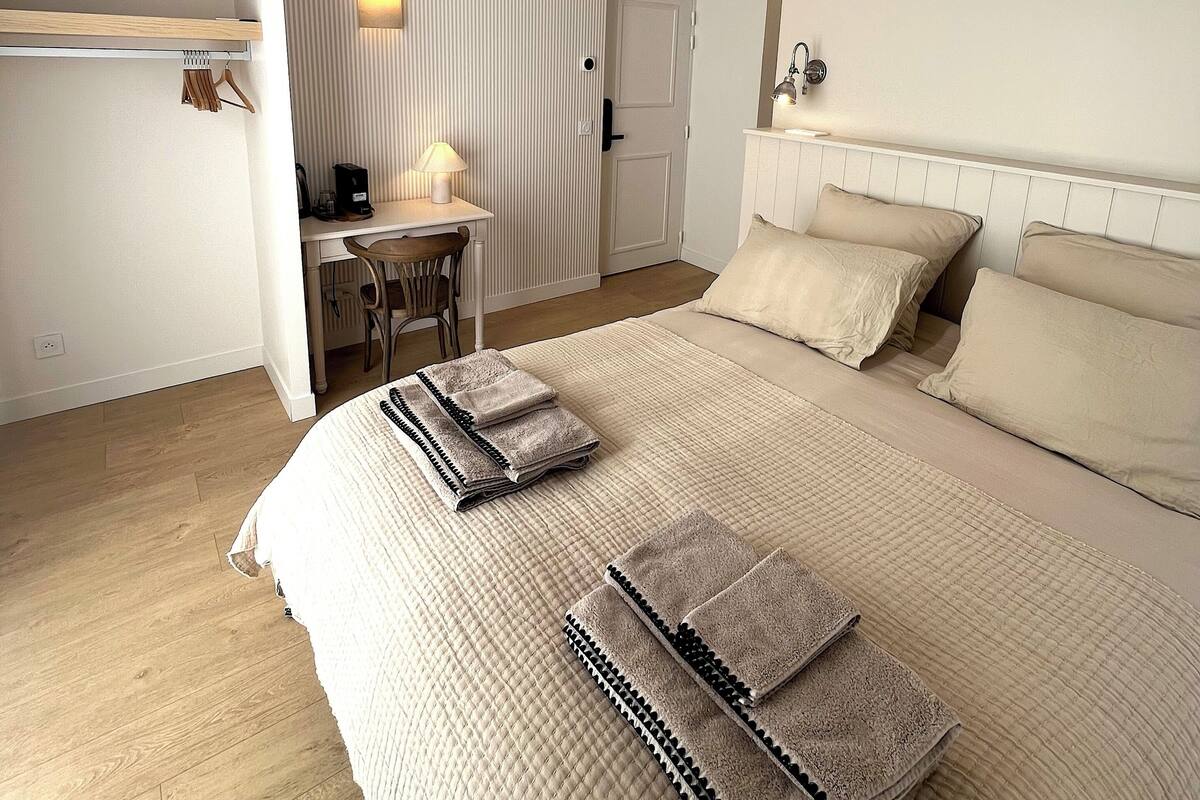 A bedroom with a bed, bedside tables, a desk, and a chair.