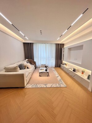 Una sala de estar moderna con un sofá, una mesa de centro y un televisor montado en la pared.