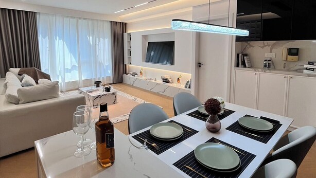 A modern living room with a sofa, a dining table set for two, and a kitchen area with cabinets and appliances. - Spacious master bedroom equipped with a private walk-in closet near Yuyuan (Shanghai)