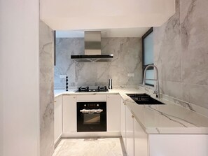 Una cocina moderna con horno empotrado, electrodomésticos de acero inoxidable y salpicadero de mármol.