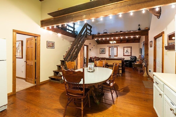 Un espace repas comprenant une table en bois, des chaises et un escalier menant à un niveau supérieur.