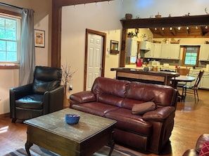 Un salon avec un canapé en cuir marron, une table basse en bois et un fauteuil en cuir noir.