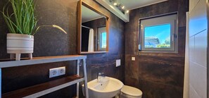 Ein modernes Badezimmer mit großem Spiegel, Waschbecken und Toilette.