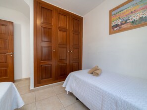 Ein Schlafzimmer mit einem Bett, einem Holzschrank und einem Bild an der Wand.