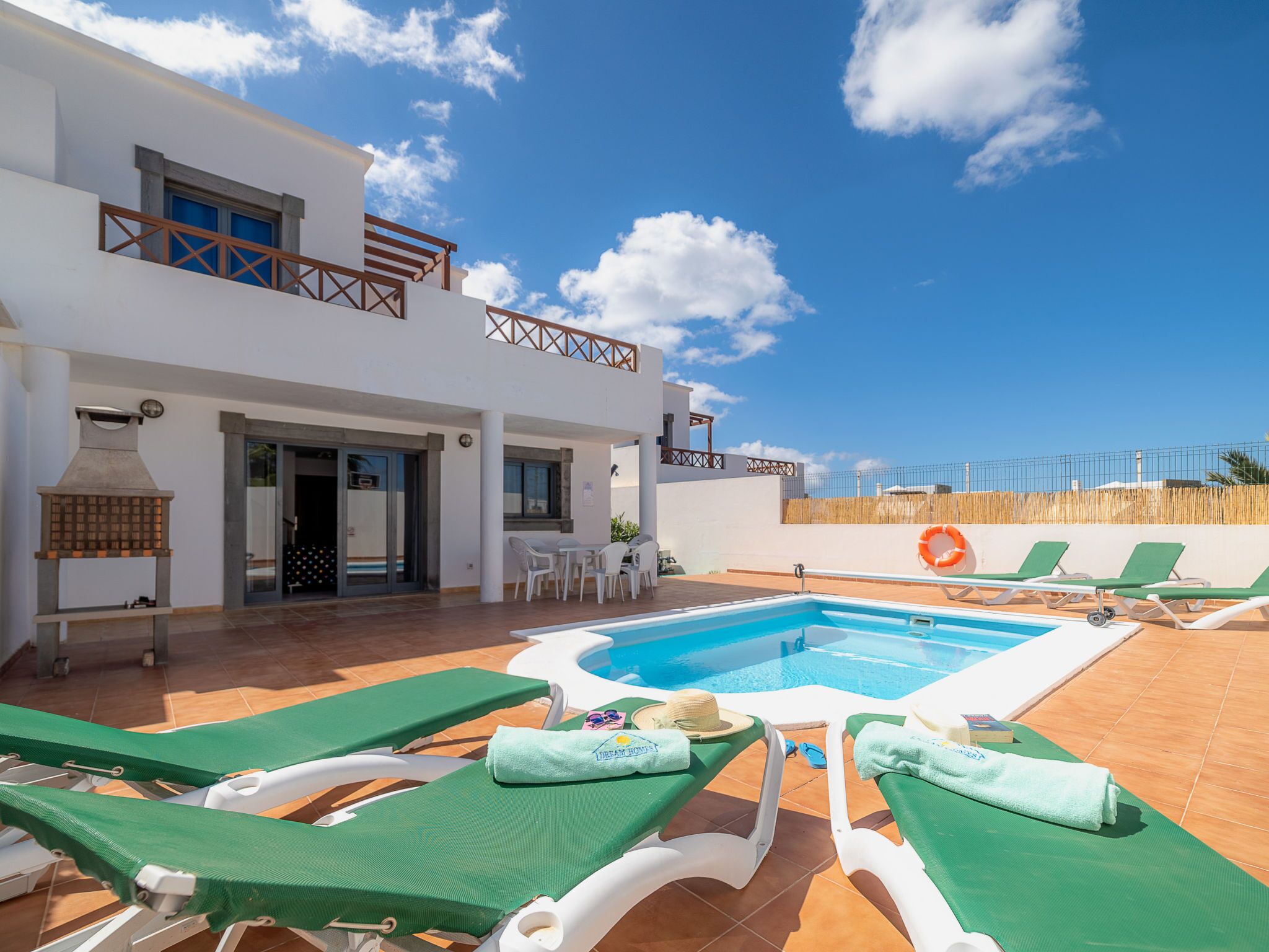 A modern villa with a pool, outdoor seating, and a clear view of the sky.