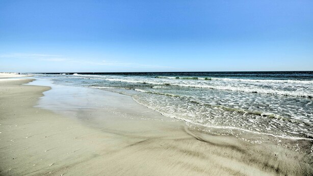 Ein Strand mit klarem Himmel und sanften Wellen.
