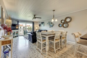 A dining area with a wooden table and chairs, a ceiling fan, and a view of the outside. - Walk to St Augustine Beach! Resort-Style Condo (St. Augustine)