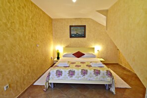 A bedroom with a bed, two bedside lamps, a painting on the wall, and a small potted plant. - Lovely Ground-floor Flat With Shared Pool in Tar (Tar-Vabriga)