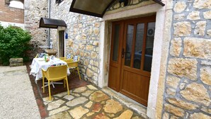 A stone building with a wooden door and a covered outdoor seating area. - Lovely Ground-floor Flat With Shared Pool in Tar (Tar-Vabriga)