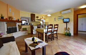 A dining area with a table set for four, a fireplace, and a television mounted on the wall. - Lovely Ground-floor Flat With Shared Pool in Tar (Tar-Vabriga)
