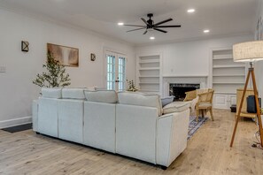A living room with a sofa, a ceiling fan, a fireplace, and built-in shelves.