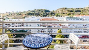 A balcony with a round table and two chairs, overlooking a residential area with white buildings and a hill in the background. - Apartment  by Interhome (Albufeira)