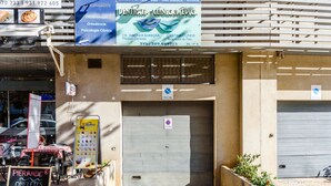 A building with a closed garage door, a signboard for a dental clinic, and a menu board for a cafe. - Apartment  by Interhome (Albufeira)