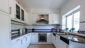 A modern kitchen with white cabinets, a stainless steel range hood, a built-in oven, and a dishwasher. - Apartment  by Interhome (Albufeira)