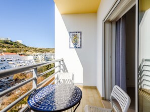A balcony with a tiled table, a chair, and a decorative plate on the wall. - Amazing Apartment in Albufeira by Interhome (Albufeira)
