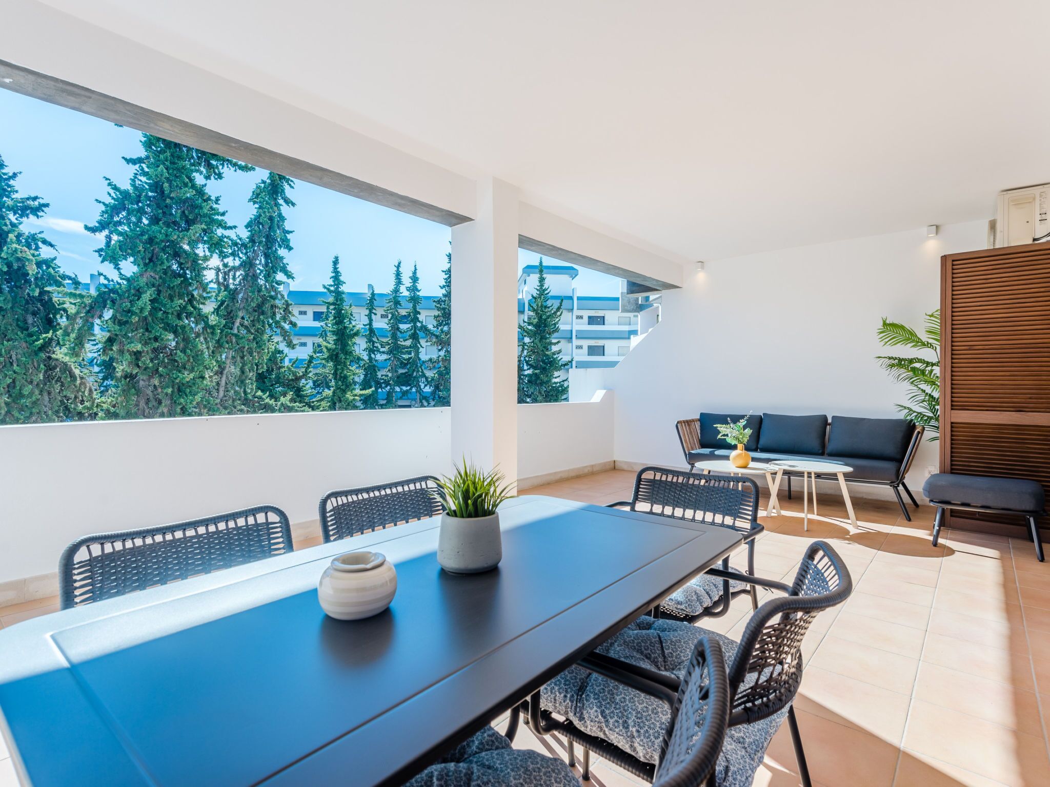 Un balcon moderne avec une table à manger, des chaises et un canapé.