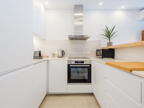 A modern kitchen with white cabinetry, a stainless steel range hood, a microwave, and a built-in oven. - Balaia apartment at Albufeira by Interhome (Albufeira)