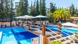 Ein Poolbereich mit mehreren Ebenen, Sonnenschirmen und Liegestühlen.