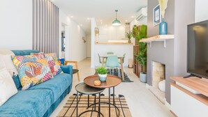 Ein modernes Wohnzimmer mit einem blauen Sofa, einem Couchtisch und einem Fernseher auf einem Holzgestell.