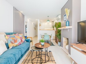 A modern living room with a blue sofa, a coffee table, and a TV on a wooden stand. - Apartment  by Interhome (Albufeira)