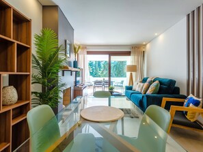 A modern living room with a glass coffee table, a blue sofa, and a wooden bookshelf. - Balaia apartment at Albufeira by Interhome (Albufeira)