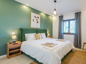 A neatly made bed with white linens, a framed botanical print on the wall, and a window with curtains. - Balaia apartment at Albufeira by Interhome (Albufeira)