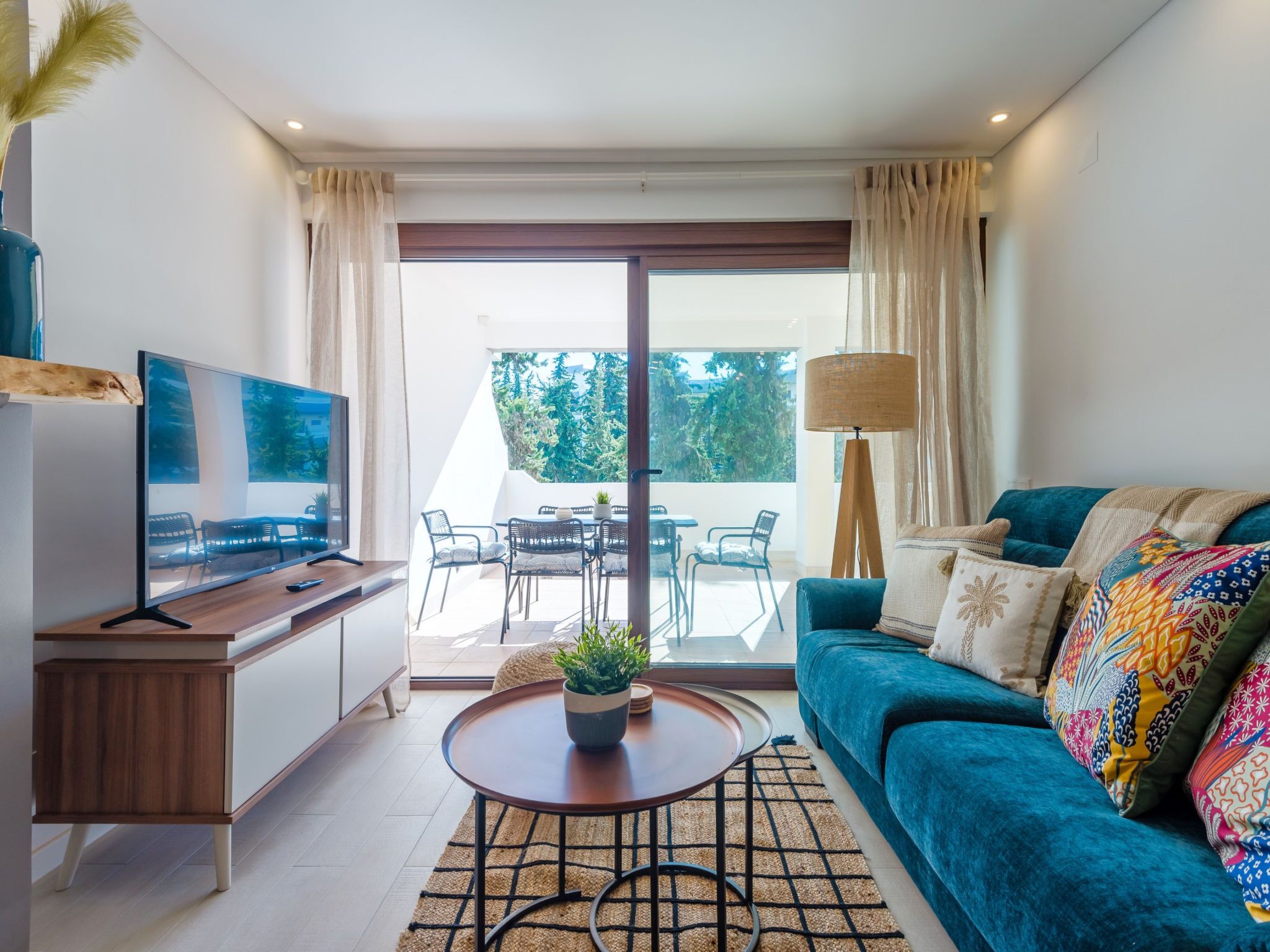 Uma sala de estar moderna com sofá, televisão e um espaço de jantar com cadeiras e mesa.