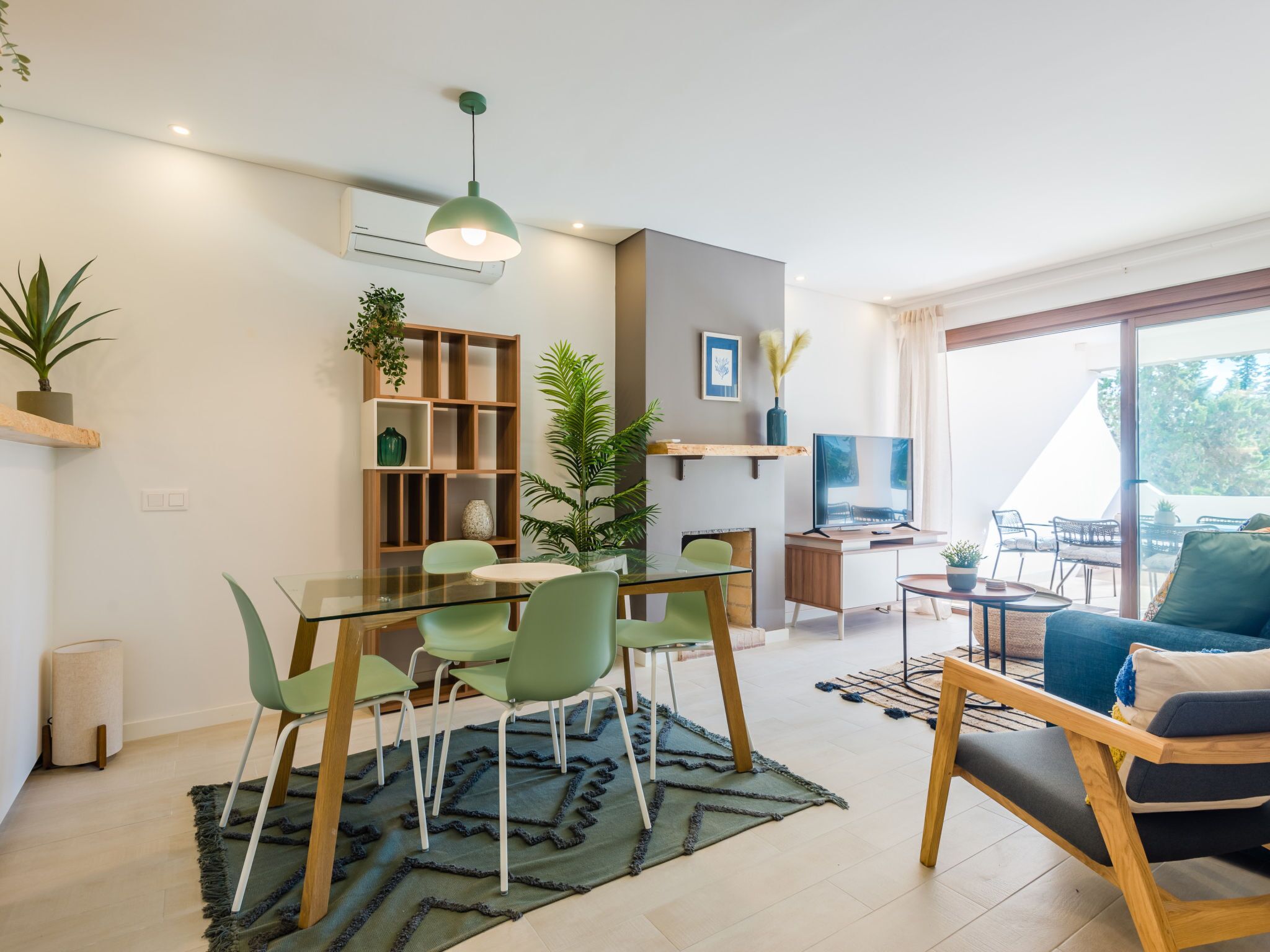 A modern living space with a dining area, a sofa, and a TV.