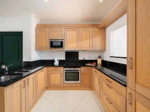 A modern kitchen with wooden cabinets, a stainless steel sink, a microwave, an oven, and a gas stove. - Apartment  by Interhome (Quarteira)