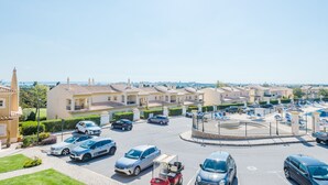 Zona residencial com um rotatório, carros estacionados e casas de arquitetura semelhante.