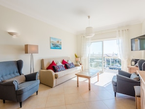 A modern living room with a sofa, two armchairs, a coffee table, and a TV. - Apartment  by Interhome (Lagos)
