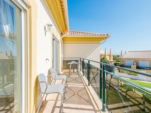 Ein Balkon mit Glasgeländer, einem Tisch und zwei Stühlen.