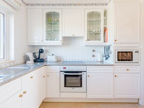 A modern kitchen with white cabinetry, a Bosch oven, and a microwave. - Apartment  by Interhome (Lagos)