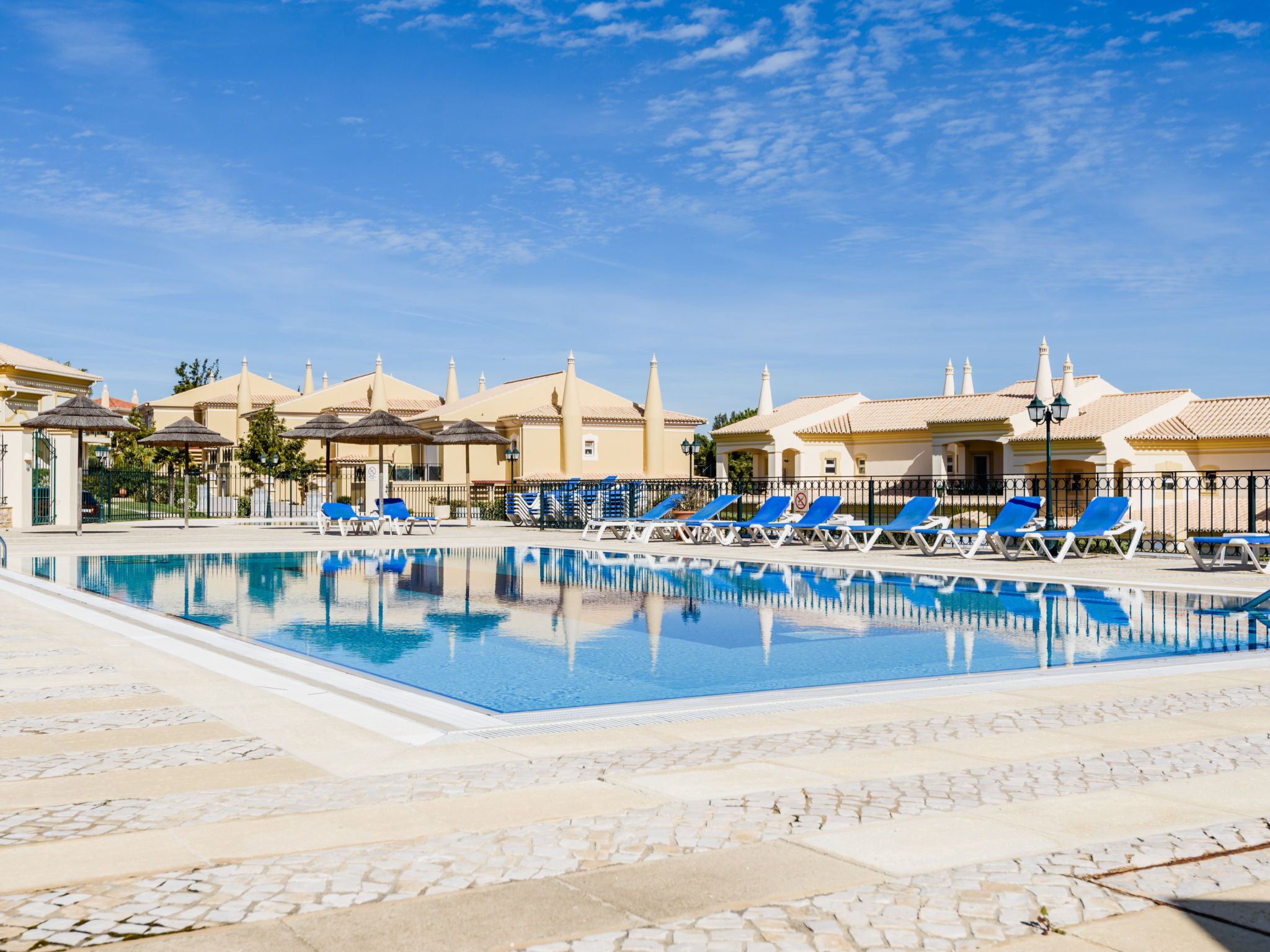 A swimming pool with lounge chairs and a building with a tiled roof.