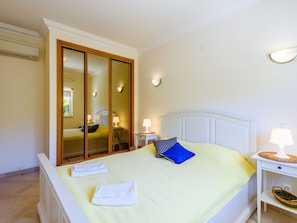 A bedroom with a bed, a bedside table with a lamp, a mirror, and a wall-mounted light fixture. - Vacation home  by Interhome (Lagos)