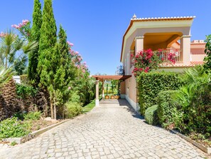 A cobblestone pathway leading to a building with a balcony adorned with pink flowers. - Casa Mapie - Boavista Golf Resort & Spa by Interhome (Lagos)