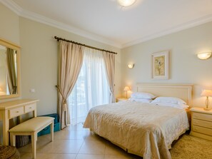 A hotel room with a bed, bedside tables, a bench, a mirror, and a window with curtains. - Vacation home  by Interhome (Lagos)