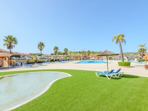 A resort with a swimming pool, lounge chairs, and palm trees. - Vacation home  by Interhome (Lagos)
