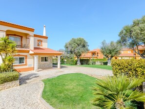 Ein Wohnhaus mit gepflasterter Auffahrt, einem gepflegten Rasen und reifen Bäumen.