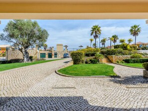 A paved courtyard with a stone pathway, green lawns, and palm trees. - Casa Sunny Days - Boavista Resort by Interhome (Lagos)