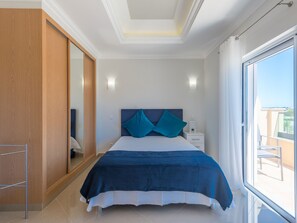 A bedroom with a bed, a nightstand, a mirror, and a view of the outdoors. - Boavista Resort - Casa Belinda by Interhome (Lagos)