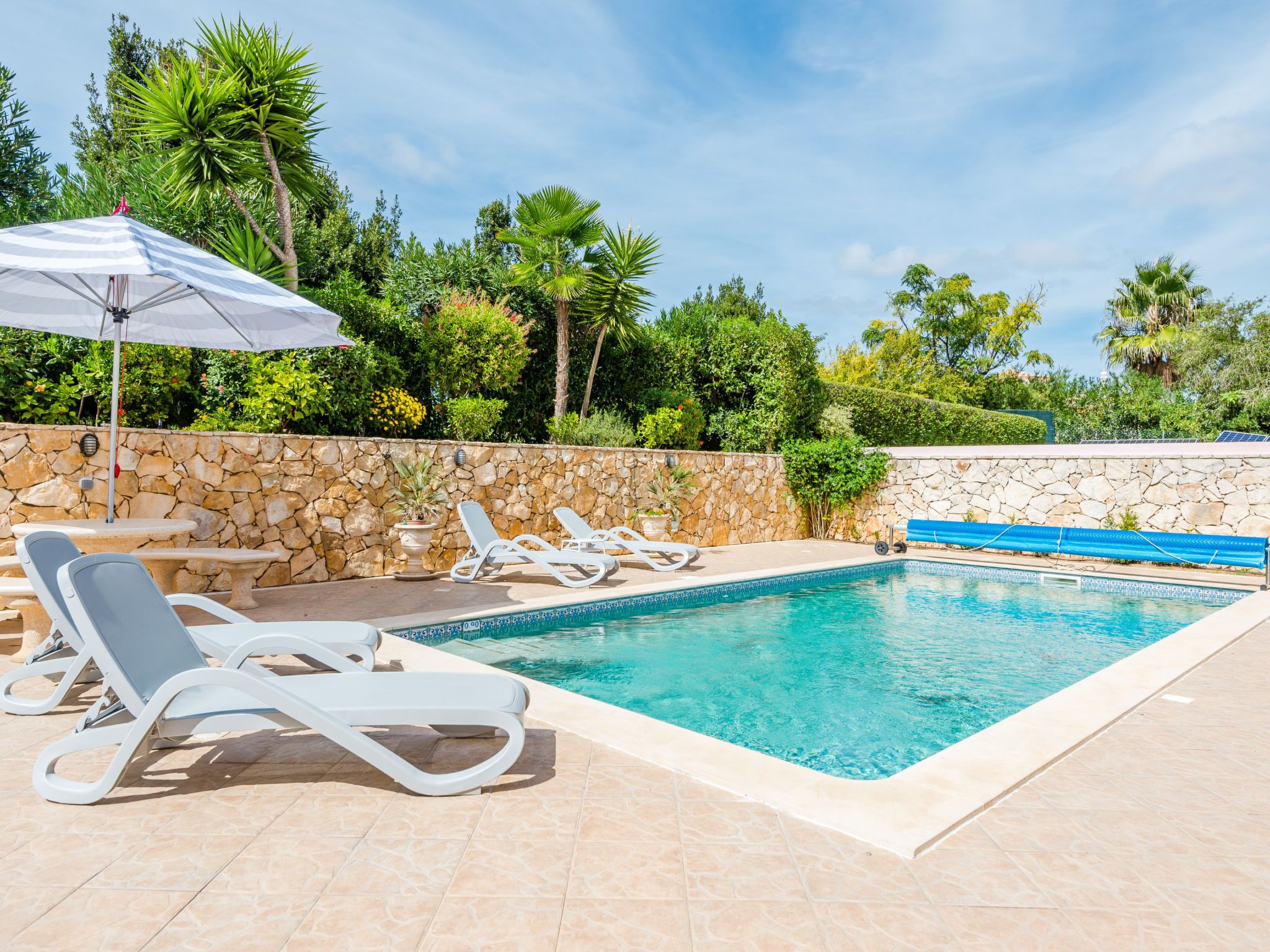 Une piscine avec des chaises longues et un mur en pierre.