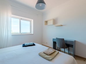 A hotel room with a bed, a desk, a chair, a window, and a ceiling light. - Casa Rosa at Boavista Resort by Interhome (Lagos)